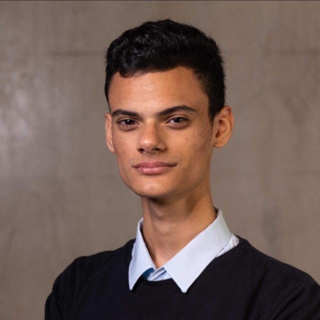 foto de oswaldo filho, homem pardo com blusa preta sorrindo.