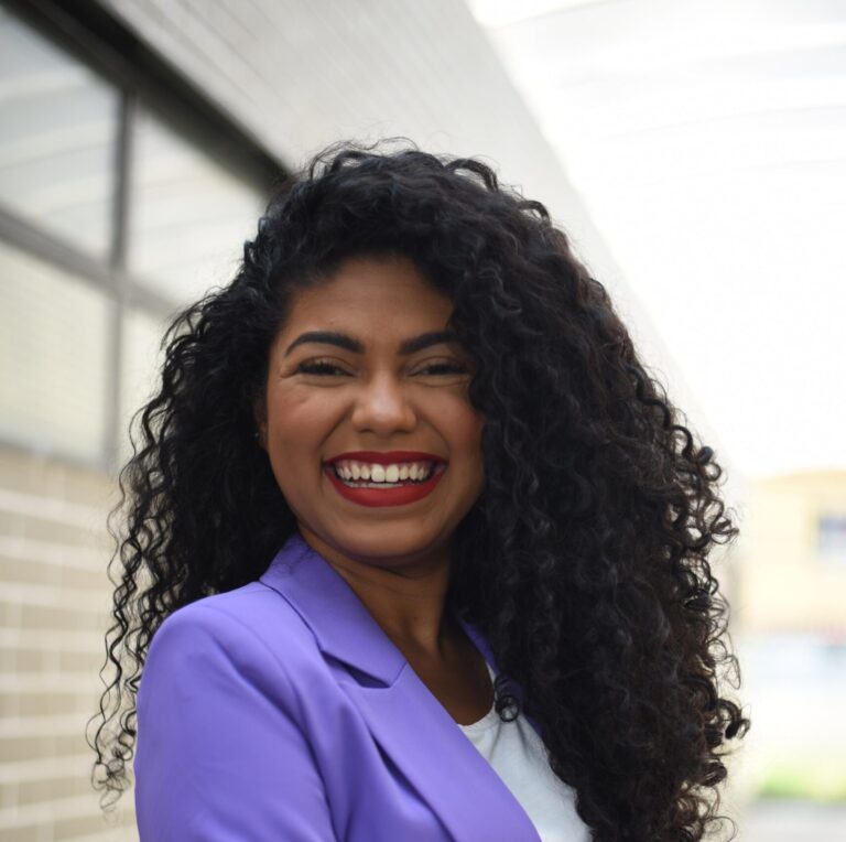 Foto de Joyce trindade - mulher negra de cabelos crespos longos em blazer roxo