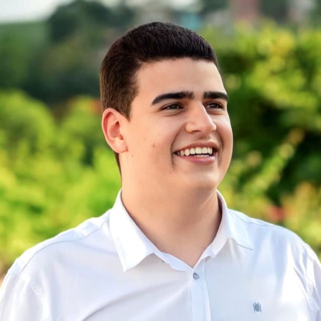 homem branco, sorrindo, com blusa branca e cabelos curtos